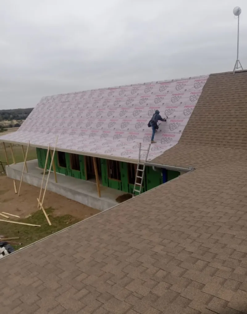 Worker preparing underlayment for a metal roof installation in Welcome